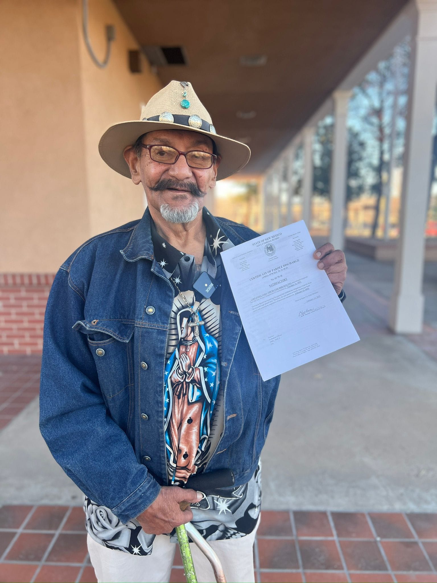 Carlos Cervantes wearing a Lupita shirt and holding the document releasing him from parole.